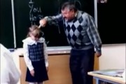 An English teacher in Russia angrily pokes a little Russian schoolgirl's head with his middle finger during a lesson.